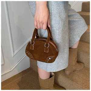 Detail of dark brown suede bowling bag with silver studs and circular top handles