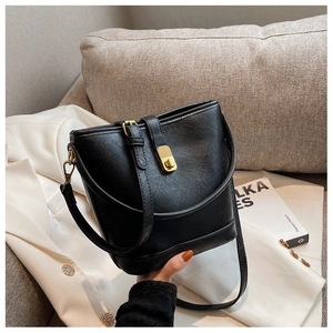 Détail du sac seau noir avec texture cuir grainé et fermoir pivotant en métal doré chic