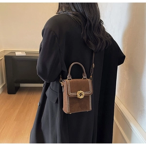 Brown box-shaped shoulder bag with gold twist buckle and white pearl bead accents
