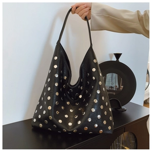 Detail of black leather tote bag with silver metal studs and wide shoulder strap