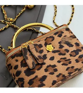 Détail du sac léopard avec insigne floral doré et bandoulière en chaîne métallique