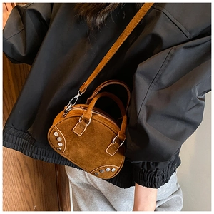 Detail of brown suede bowling bag with silver rivets and detachable shoulder strap