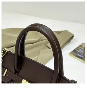Détail d'un sac en cuir litchi marron chocolat avec boucles dorées et anses rondes