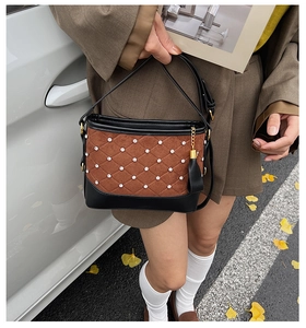Close-up of quilted brown suede shoulder bag with rhinestone details and black leather trim