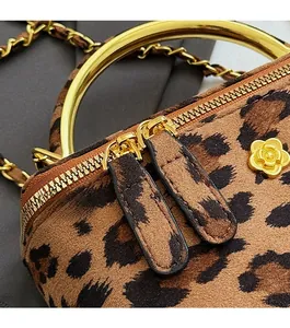 Détail du sac à main léopard montrant le zip camélia doré et la poignée en anneau