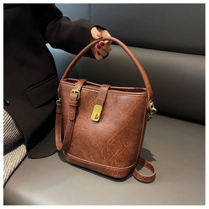 Détail d'un sac seau vintage marron avec fermoir rotatif en métal et bandoulière réglable