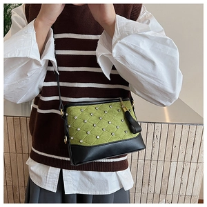 Detail of green suede crossbody bag featuring rhinestone quilted pattern and black tassels