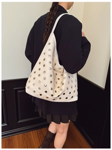 Close-up of soft cream leather tote bag featuring decorative silver metal studs