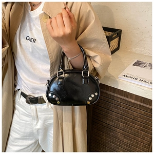 Detail of a retro black bowling bag featuring silver studs and glossy PU leather finish