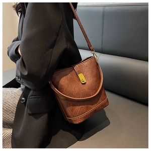 Sac seau vintage en cuir marron porté en bandoulière sur une veste de blazer noire