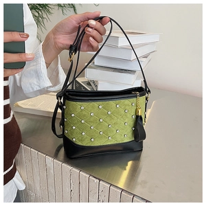Detail of green and black contrast bag featuring diamond stitching and rhinestone accents