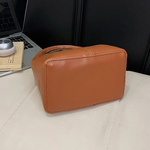 Détail du logo embossé et du zip sur le sac en cuir marron avec accessoires modernes