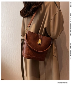 Détail d'un sac seau en cuir marron avec fermoir pivotant doré et texture grainée