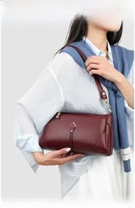 Detail of burgundy leather shoulder bag featuring gold leaf metal decoration on the front