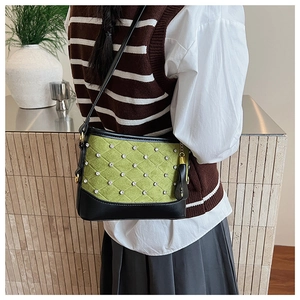 Detail of green quilted shoulder bag with rhinestones and black leather accents