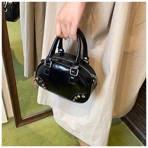 Close-up of black glossy patent leather bowling bag featuring silver rivet details