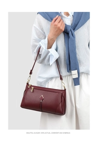 Detail of burgundy lychee leather bag featuring a gold tulip-shaped clasp and zipper