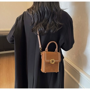 Side view of dark brown retro crossbody bag with gold knot buckle on a black coat