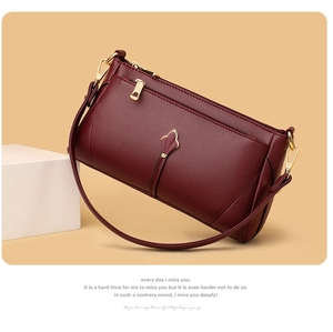 Detail of burgundy lychee leather shoulder bag with elegant golden hardware and floral clasp