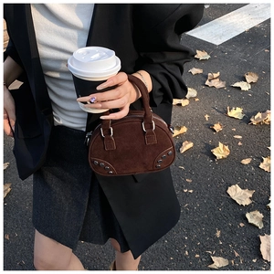 Close-up of vintage dark brown suede bowling bag with silver studs on autumn street