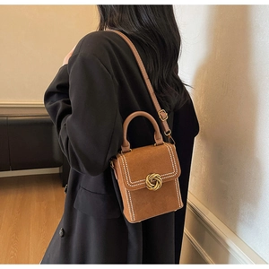 Detail of vintage brown matte leather handbag with gold knot clasp and white stitching