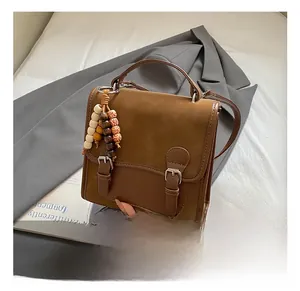 Dettaglio borsa in pelle marrone vintage con fibbia retrò e ciondolo in perle di legno