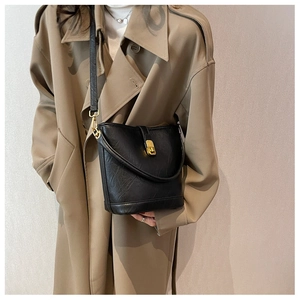 Détail du sac seau noir vintage avec fermoir en métal doré porté par un mannequin chic
