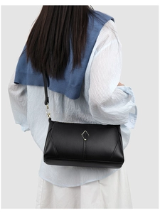 Close-up of black lychee grain leather shoulder bag with a metallic geometric emblem