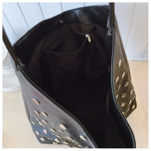 Detail view of the black studded shoulder bag with a spacious interior and zipper pocket