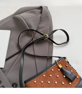 Detail of brown suede bucket bag featuring rhinestone accents and black leather fringe