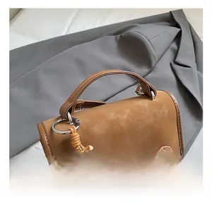 Dettaglio della borsa a tracolla marrone vintage con trama opaca e ciondolo di perle