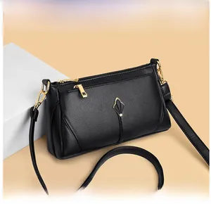 Detail of black pebbled leather crossbody bag with gold-tone leaf metal fastener