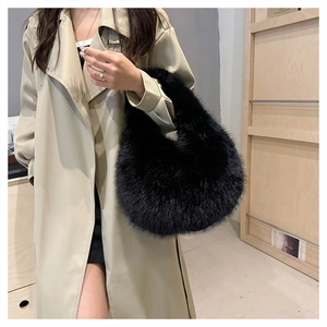 Detail of black faux fur handbag with plush texture held by a model in a trench coat