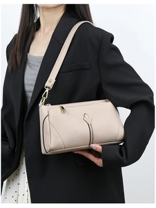 Detail view of beige lychee texture shoulder bag with gold hardware on a model