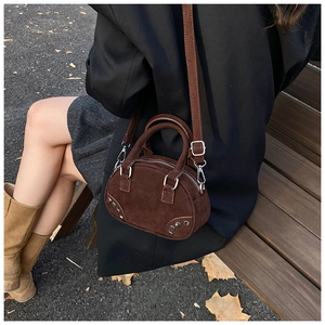 Side view of dark brown frosted leather bowling bag with vintage rivet details on a model
