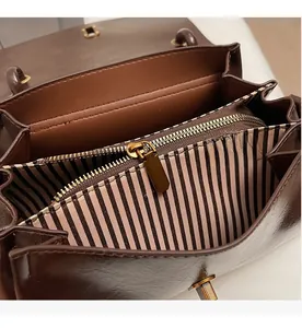Detail view of the brown leather bag interior with striped lining and three compartments