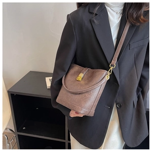 Gros plan du sac seau marron foncé avec fermoir rotatif doré et texture rétro vintage