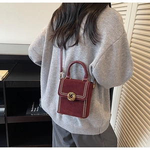Detail of burgundy suede handbag with pearl trim and golden woven buckle on model