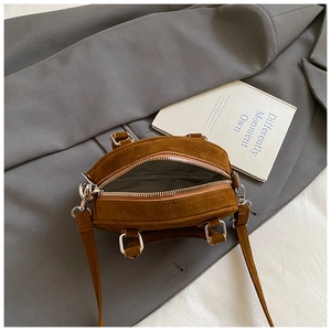 Detail view of the brown suede bowling bag showing the zipper and gray fabric interior