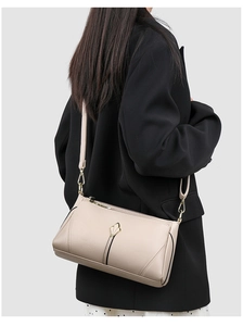 Detail of beige lychee textured shoulder bag with golden leaf-shaped metal hardware
