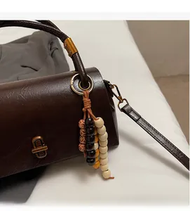 Detail of dark brown glossy leather bag featuring a retro gold buckle and colorful wood beads