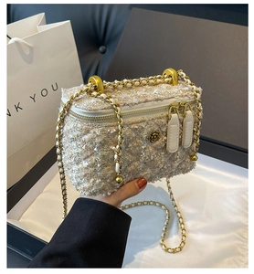 Detail of tweed crossbody box bag featuring gold camellia hardware and chain strap