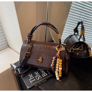 Détail du sac vintage marron foncé avec fermoir doré et pendentif en perles de bois