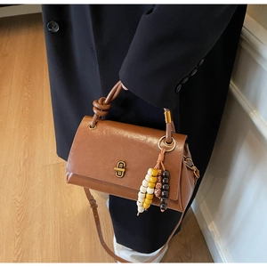 Detailed view of a brown vintage tote bag with gold lock and colorful beaded tassel