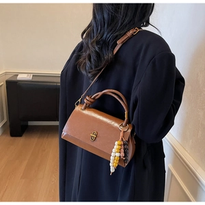 Détail du sac en cuir marron vintage avec fermoir en métal et breloques en perles de bois