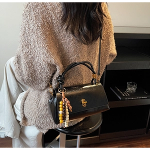 Modèle portant un sac baguette noir vintage avec fermoir doré et détail de perles