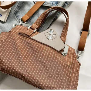 Vista macro dettagliata della tasca frontale con zip su una borsa a tracolla a scacchi