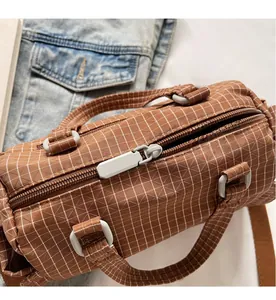 Dettaglio di una borsa Boston a quadretti marroni con cerniera liscia e trama fine
