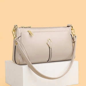 Chic beige lychee leather crossbody bag for women with gold hardware on white stand