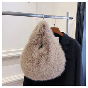 Detail of minimalist beige faux fur knotted handbag on a metallic hanger with black blazer